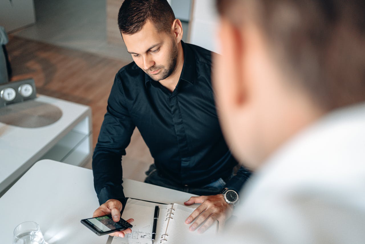 Professional man checking smartphone during a business meeting in a modern office setting.